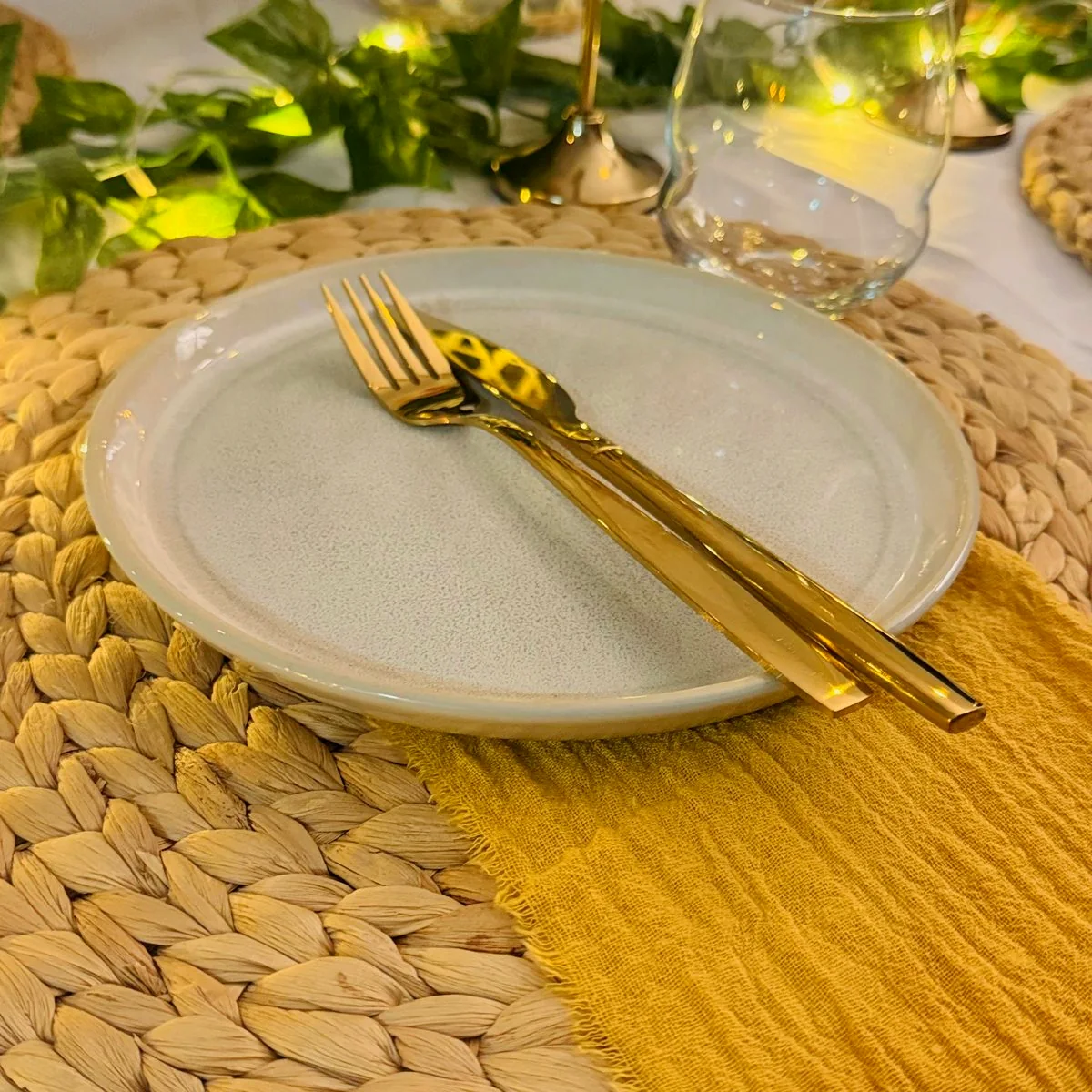 Close-up of a real Harmony Moments place setting with gold cutlery and woven placemat