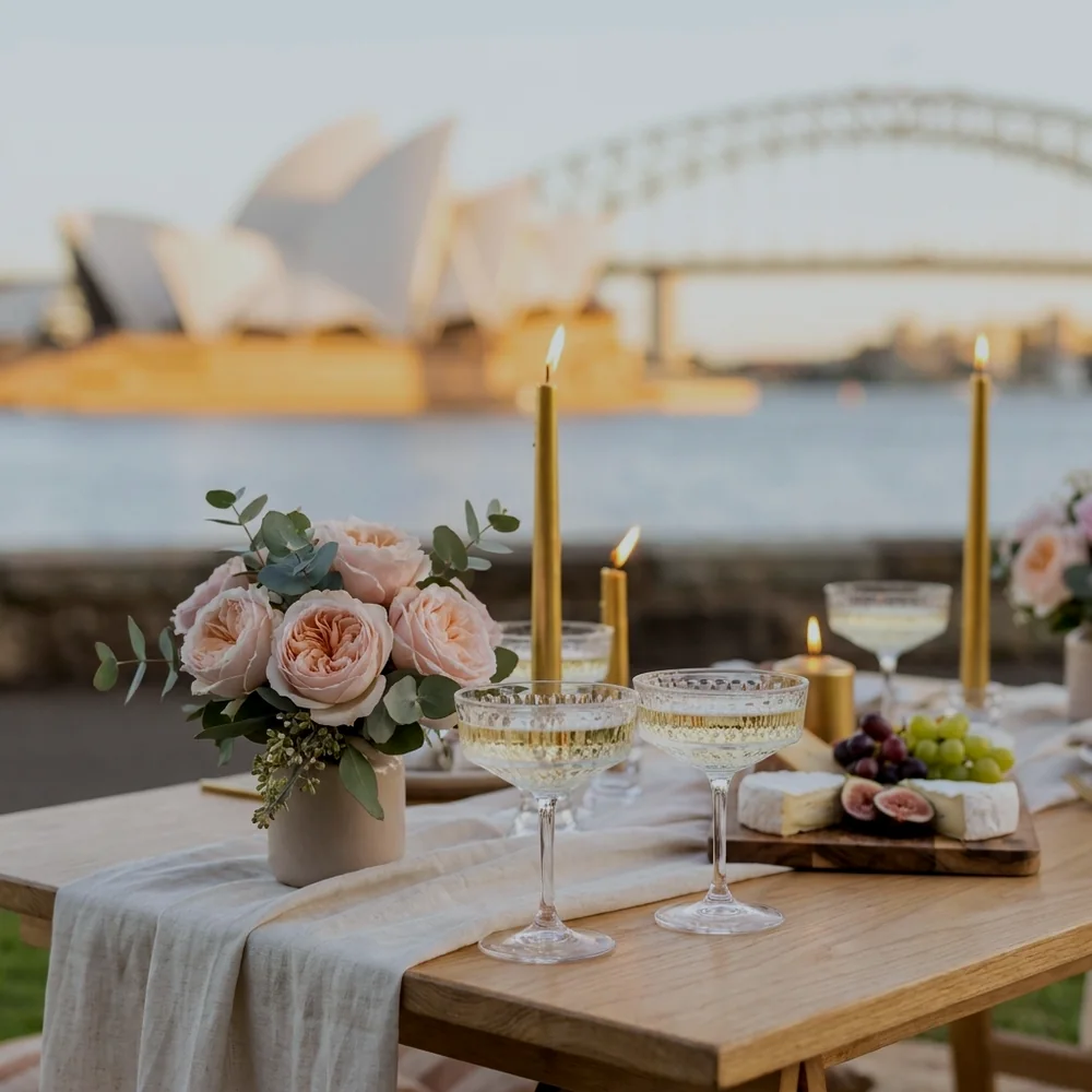 Close-up of a date night tablescape with champagne coupes, blush roses and gold candles