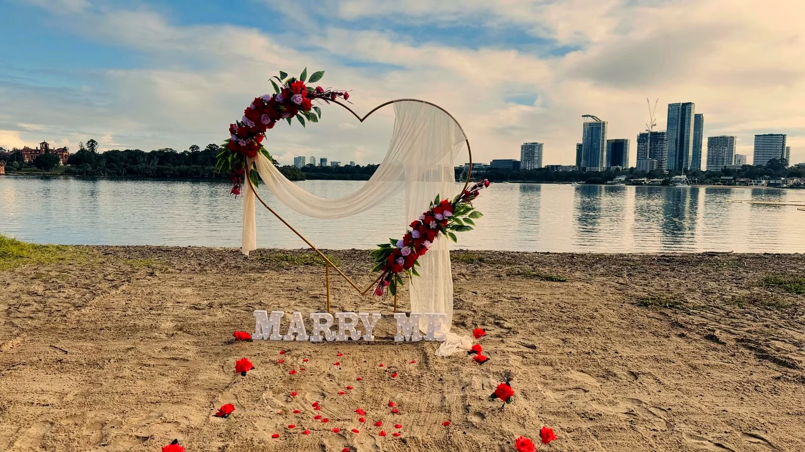 Floral heart arch with MARRY ME letters styled by Harmony Moments on a Sydney beach